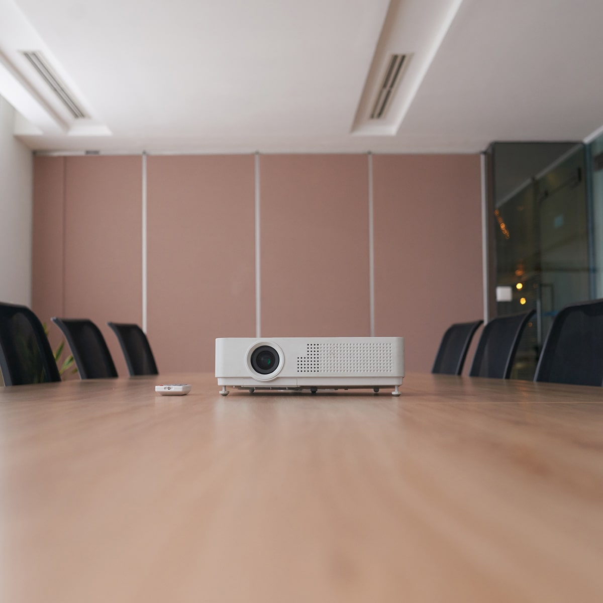 pan-shot-empty-office-with-projector-middle-conference-desk-min